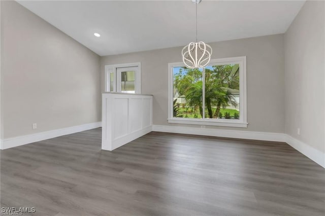 unfurnished dining area featuring dark wood-type flooring and a notable chandelier