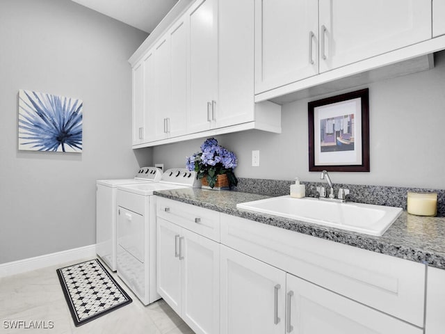 clothes washing area with washer and dryer, cabinets, and sink