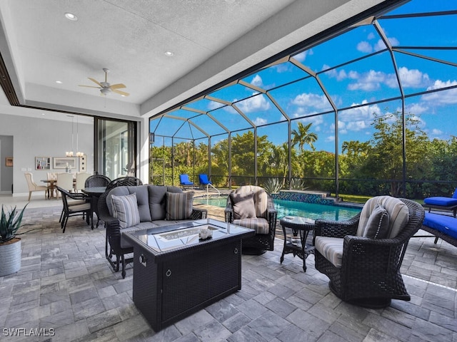 view of patio with a lanai, ceiling fan, and an outdoor living space with a fire pit