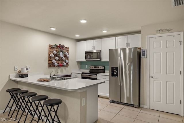 kitchen featuring kitchen peninsula, stainless steel appliances, and white cabinetry