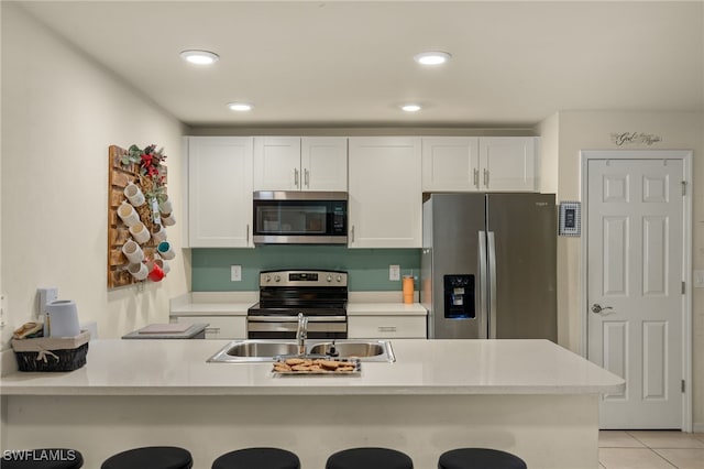 kitchen with kitchen peninsula, a breakfast bar, stainless steel appliances, sink, and white cabinets