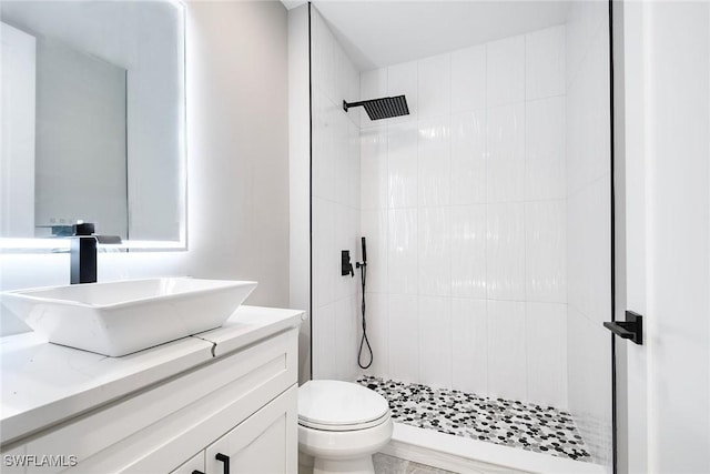 bathroom featuring vanity, toilet, and tiled shower