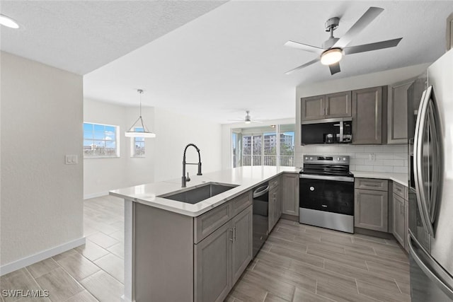 kitchen featuring pendant lighting, sink, decorative backsplash, appliances with stainless steel finishes, and kitchen peninsula