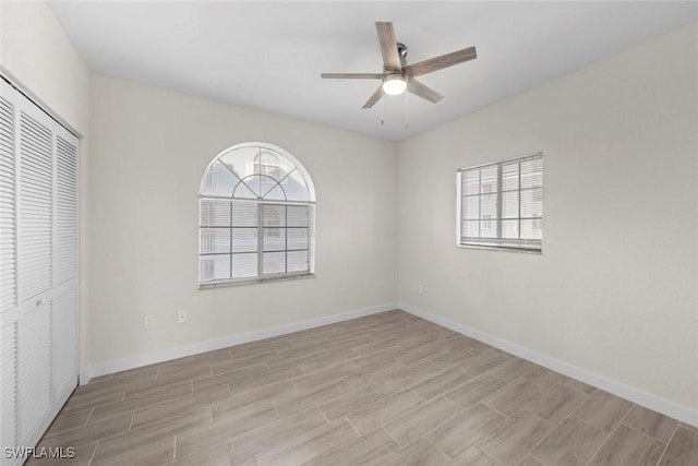 unfurnished bedroom with multiple windows, ceiling fan, and a closet