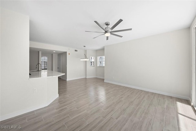 unfurnished living room featuring ceiling fan and sink