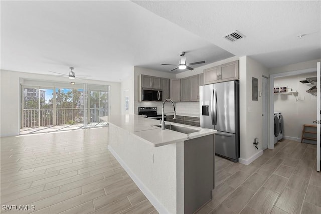 kitchen with decorative backsplash, gray cabinetry, stainless steel appliances, washer and clothes dryer, and sink