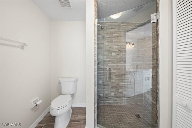 bathroom featuring a shower with door and toilet