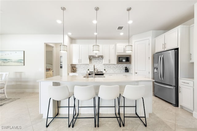 kitchen featuring pendant lighting, backsplash, a kitchen island with sink, white cabinetry, and stainless steel appliances