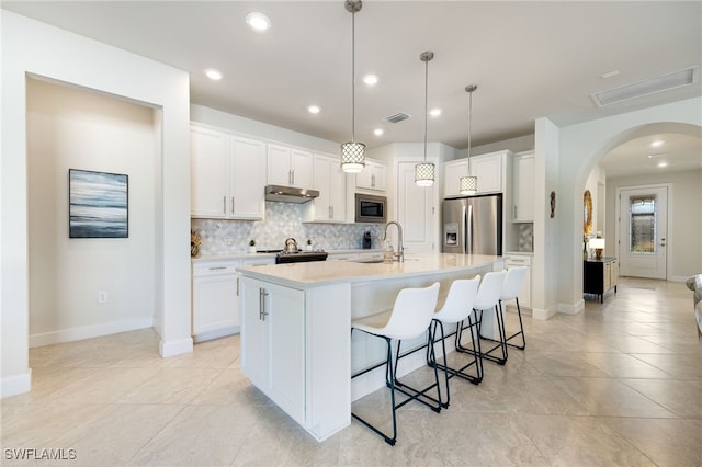 kitchen with a center island with sink, white cabinets, sink, decorative light fixtures, and stainless steel appliances