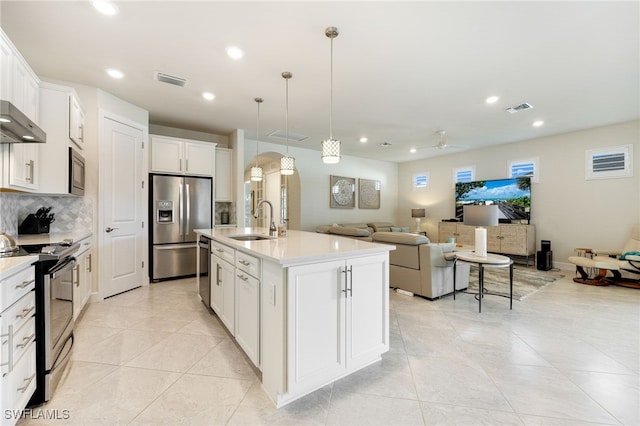 kitchen with a kitchen island with sink, white cabinets, sink, appliances with stainless steel finishes, and decorative light fixtures