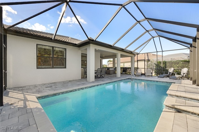 view of swimming pool featuring ceiling fan, a lanai, a mountain view, and a patio