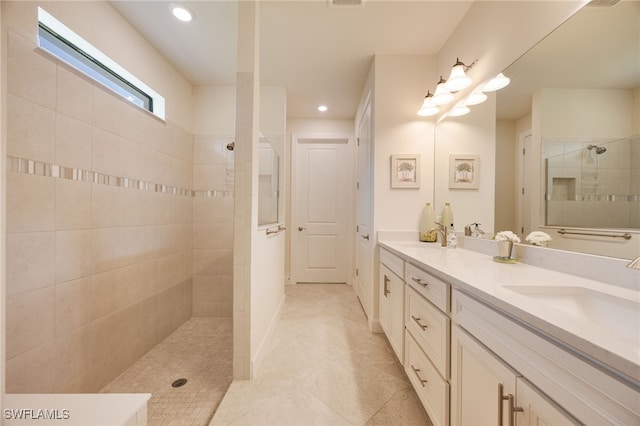 bathroom featuring tile patterned floors, vanity, and a tile shower