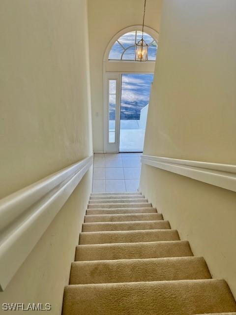 stairway featuring a chandelier and tile patterned floors