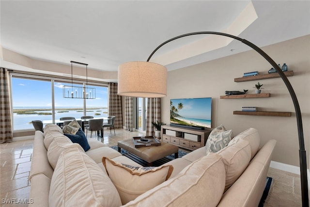 living room featuring a chandelier, baseboards, and stone tile flooring