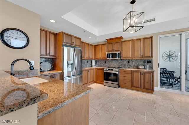 4951 Bonita Bay Blvd Unit 1804, Bonita Springs, FL 34134 - kitchen with brown cabinets, a sink, a tray ceiling, appliances with stainless steel finishes, and light stone countertops