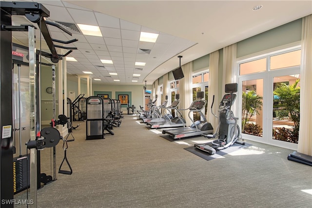 gym with a paneled ceiling and carpet