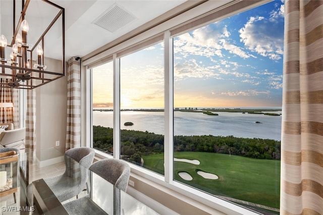 dining room with visible vents, a water view, baseboards, and a chandelier