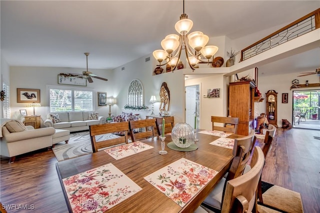 dining space featuring ceiling fan with notable chandelier, dark hardwood / wood-style flooring, a wealth of natural light, and vaulted ceiling