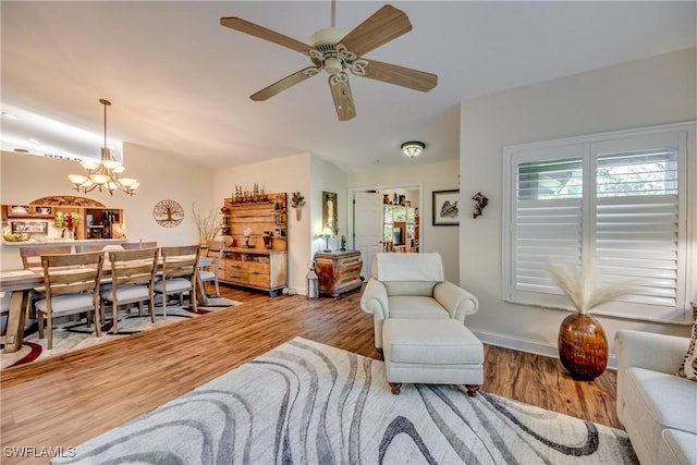 living room with hardwood / wood-style flooring and ceiling fan with notable chandelier