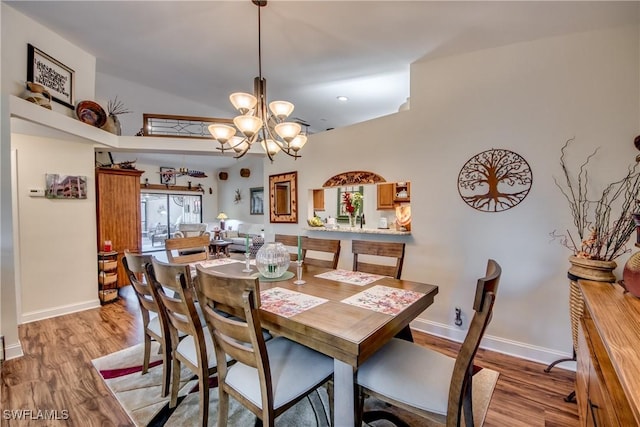 dining area with a high ceiling, light hardwood / wood-style floors, and an inviting chandelier