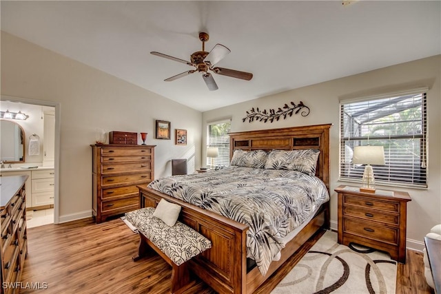 bedroom with ceiling fan, vaulted ceiling, light hardwood / wood-style flooring, and ensuite bath