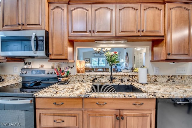 kitchen featuring light stone countertops, appliances with stainless steel finishes, a notable chandelier, and sink