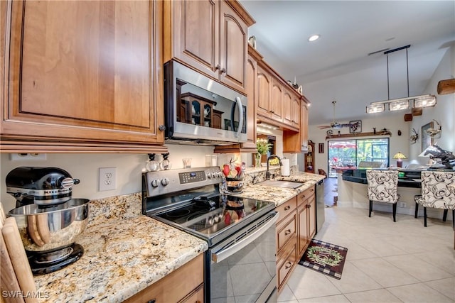 kitchen featuring sink, stainless steel appliances, light stone counters, pendant lighting, and light tile patterned floors