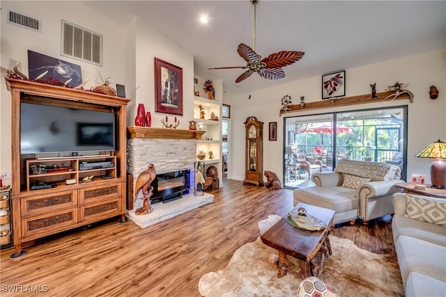 living room with ceiling fan, light hardwood / wood-style floors, and a stone fireplace