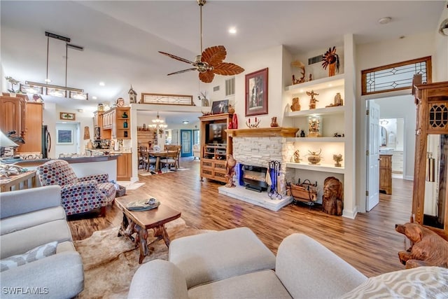 living room with ceiling fan, high vaulted ceiling, built in features, a fireplace, and light hardwood / wood-style floors