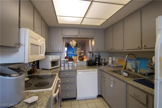 kitchen featuring gray cabinetry, white appliances, sink, light tile patterned floors, and a notable chandelier