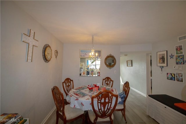 dining space with wood-type flooring and an inviting chandelier