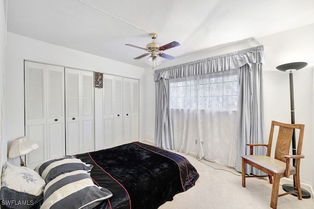 bedroom with ceiling fan, light carpet, and multiple closets