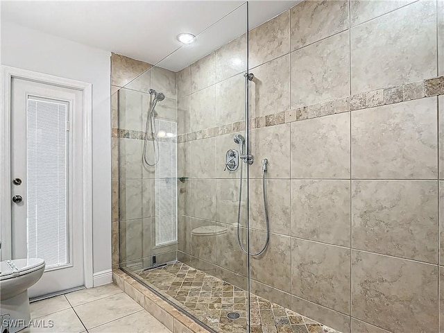 bathroom with a tile shower, tile patterned flooring, and toilet