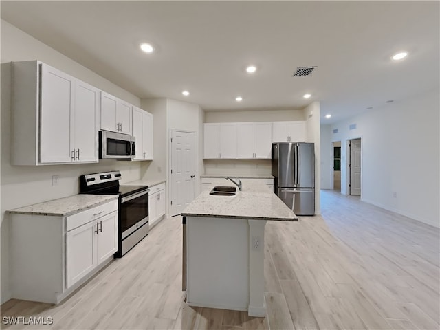 kitchen with stainless steel appliances, white cabinetry, a center island with sink, and sink