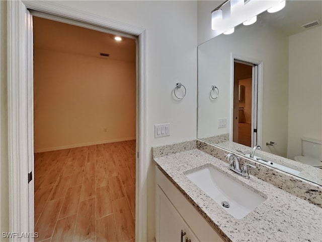 bathroom with toilet, vanity, and hardwood / wood-style flooring