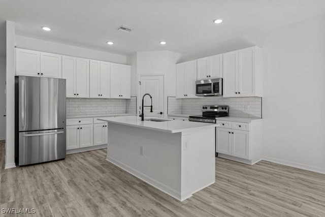 kitchen with light countertops, appliances with stainless steel finishes, a sink, and light wood-style floors