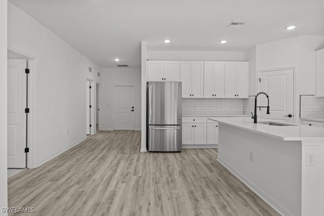 kitchen with visible vents, light countertops, a sink, and freestanding refrigerator