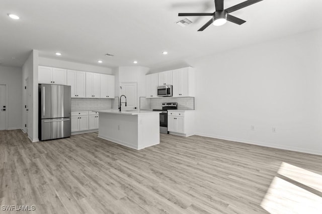 kitchen featuring open floor plan, stainless steel appliances, tasteful backsplash, and light countertops