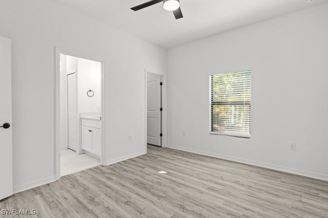 unfurnished bedroom with light wood-style flooring, baseboards, ceiling fan, and connected bathroom