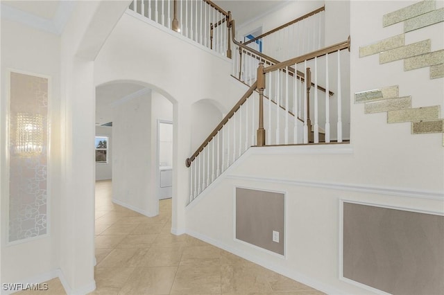 stairway with a towering ceiling and ornamental molding