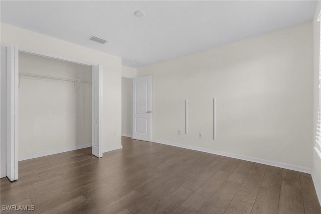 unfurnished bedroom with dark hardwood / wood-style floors and a closet