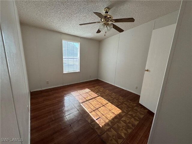 spare room with ceiling fan, dark wood-type flooring, and a textured ceiling