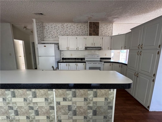 kitchen featuring a textured ceiling, white cabinetry, dark wood-type flooring, and white appliances