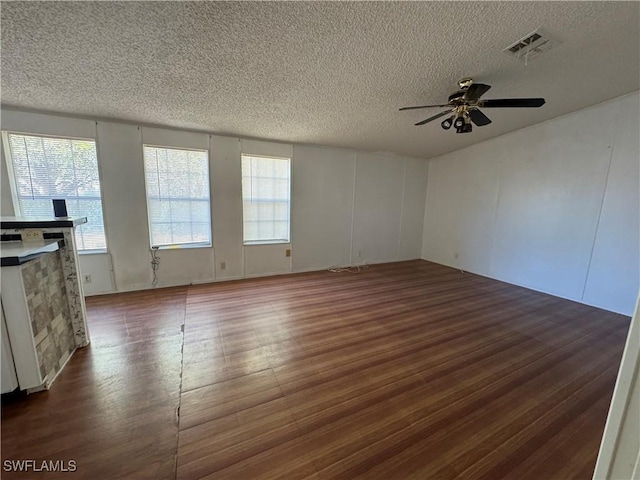 empty room with a textured ceiling, dark hardwood / wood-style floors, and ceiling fan