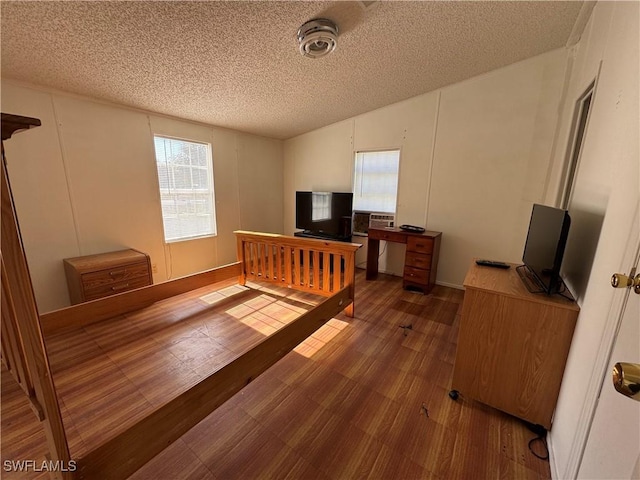 bedroom featuring dark hardwood / wood-style flooring, a textured ceiling, and vaulted ceiling