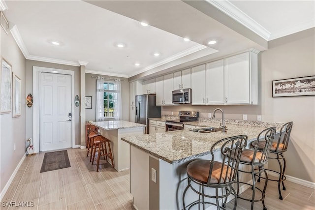 kitchen featuring sink, a breakfast bar area, a kitchen island, white cabinetry, and stainless steel appliances