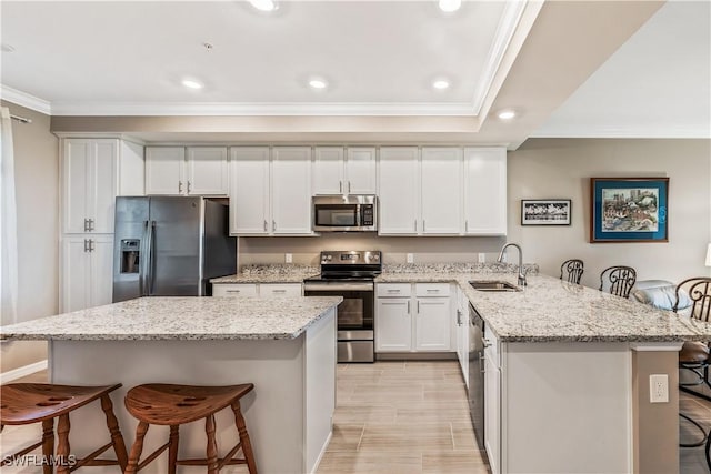 kitchen with white cabinetry, sink, light stone countertops, stainless steel appliances, and a kitchen breakfast bar