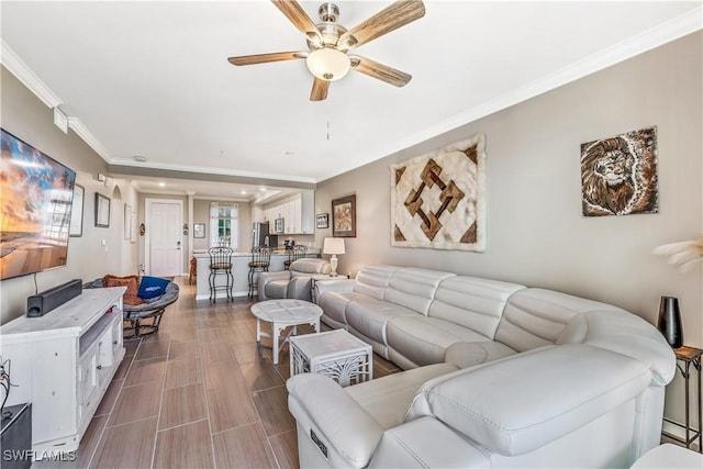 living room with ceiling fan and ornamental molding