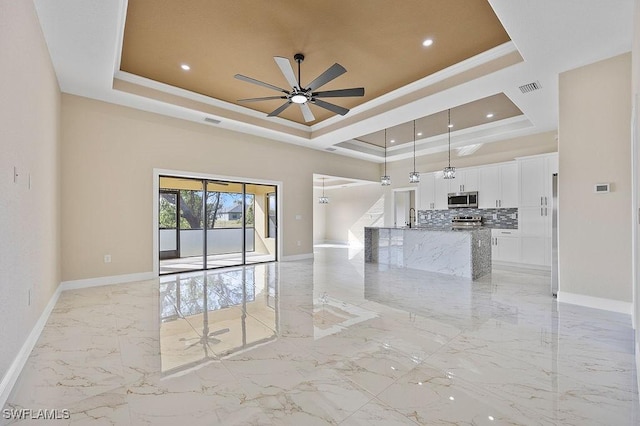 spare room featuring a raised ceiling, ceiling fan, crown molding, and sink