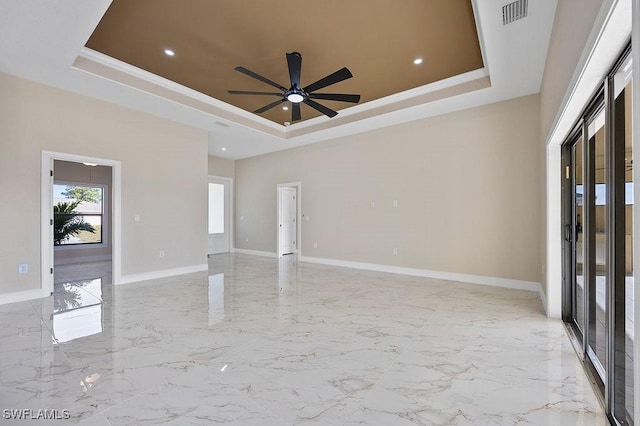 empty room featuring a tray ceiling and ceiling fan